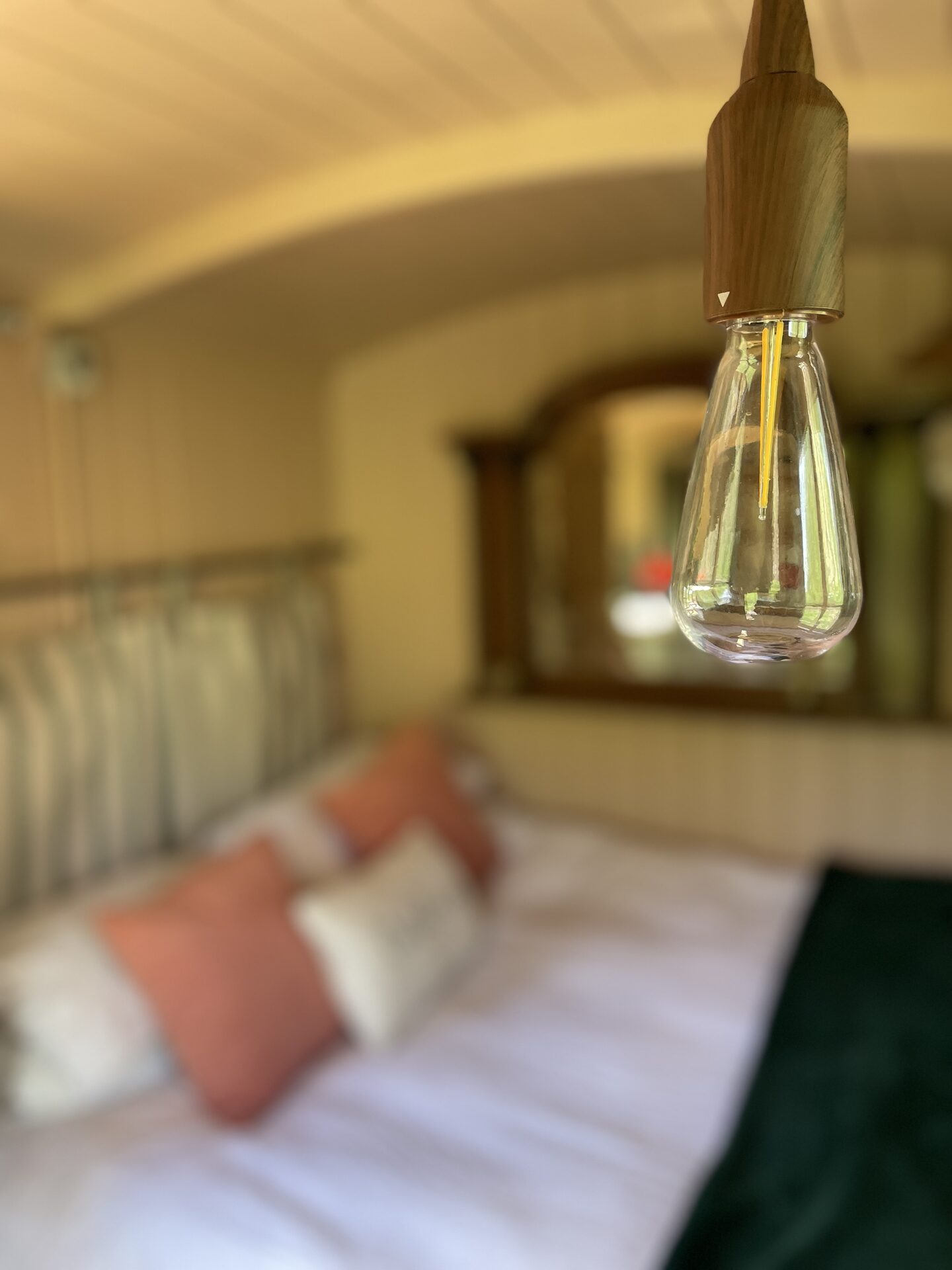 Warm Edison bulb glow over the bed inside Dolly the Hut