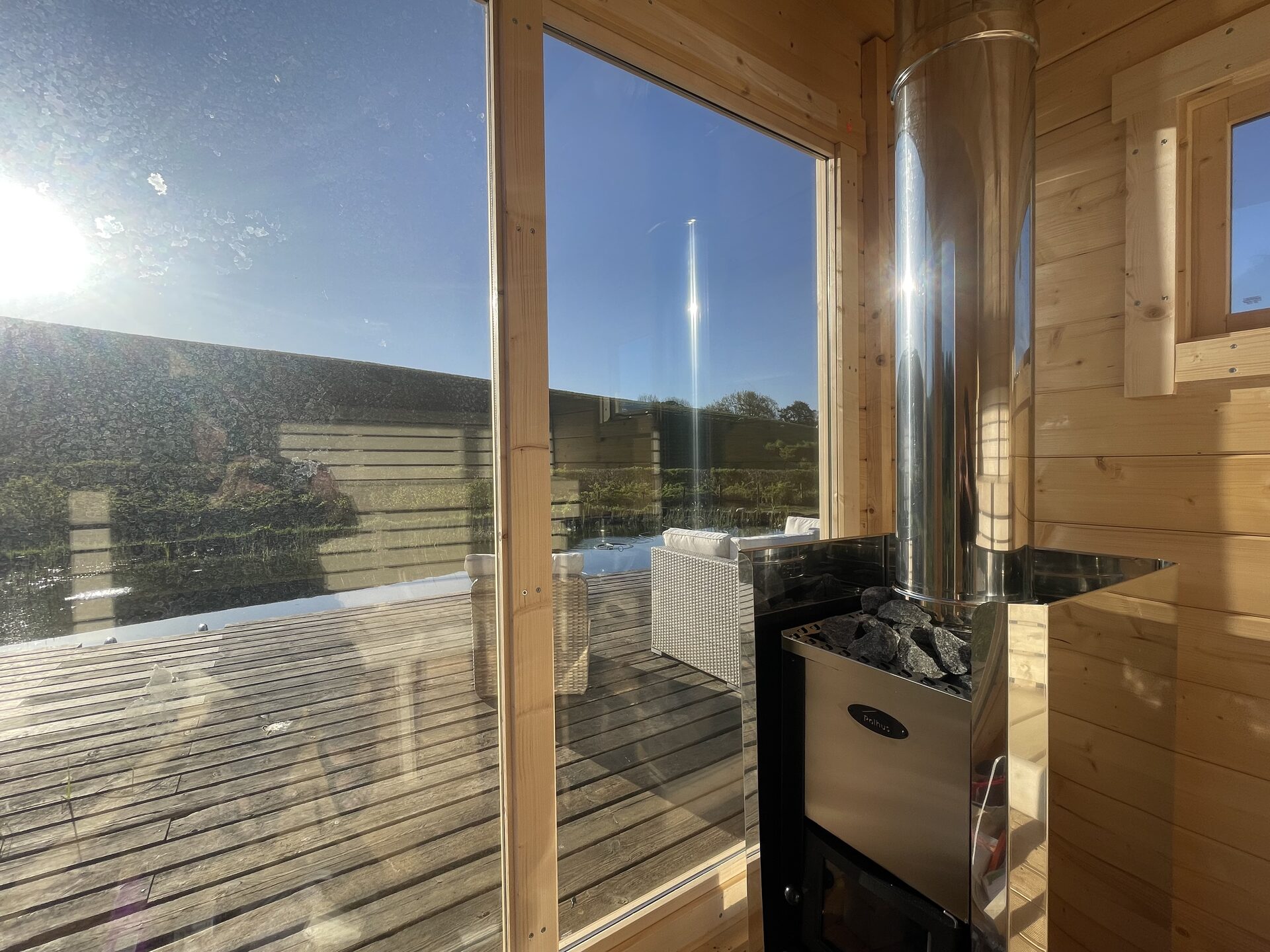 Inside the woodfired sauna looking out through the glass front to the deck