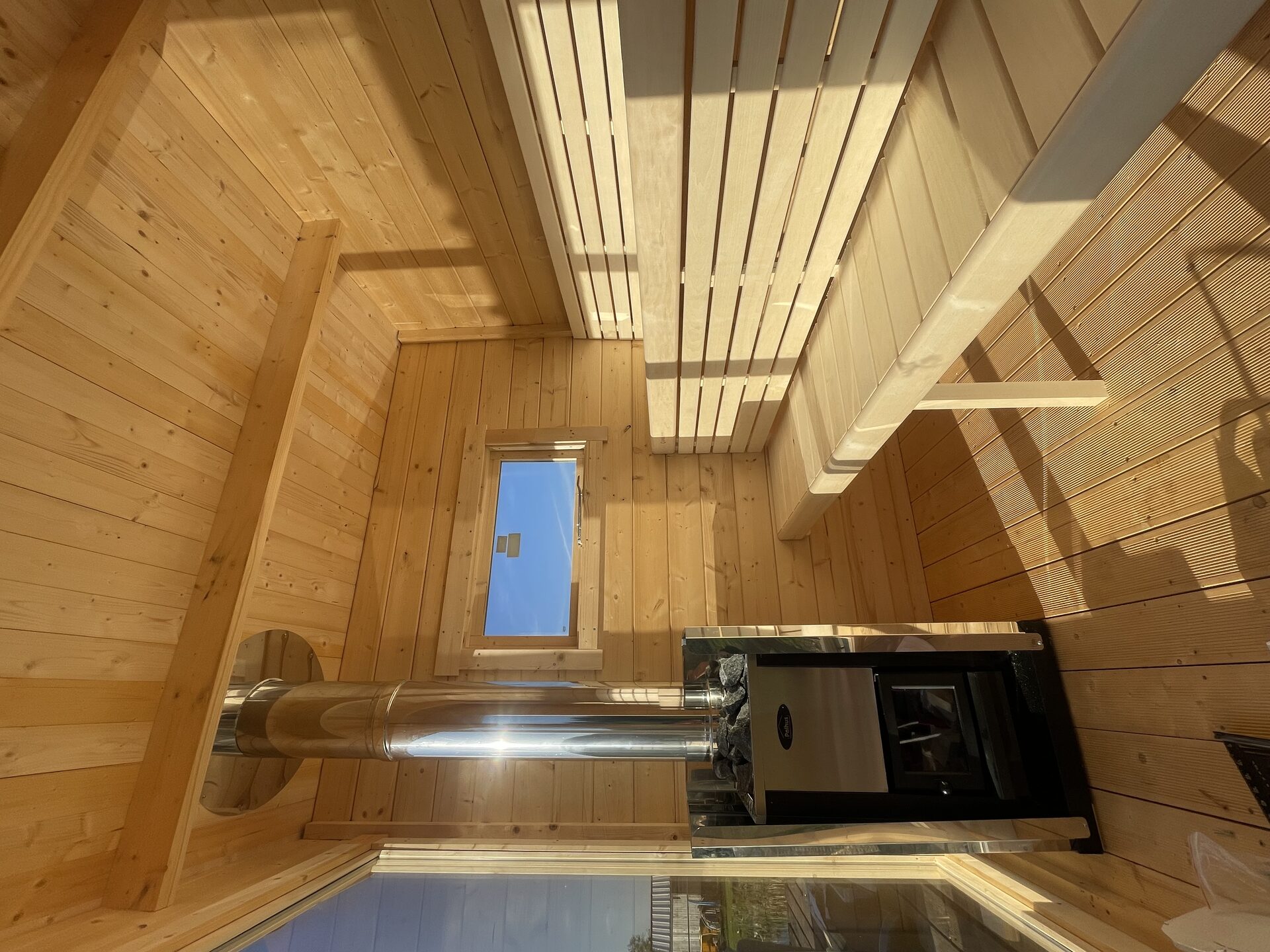 Spruce-lined sauna interior with woodburning stove and benches