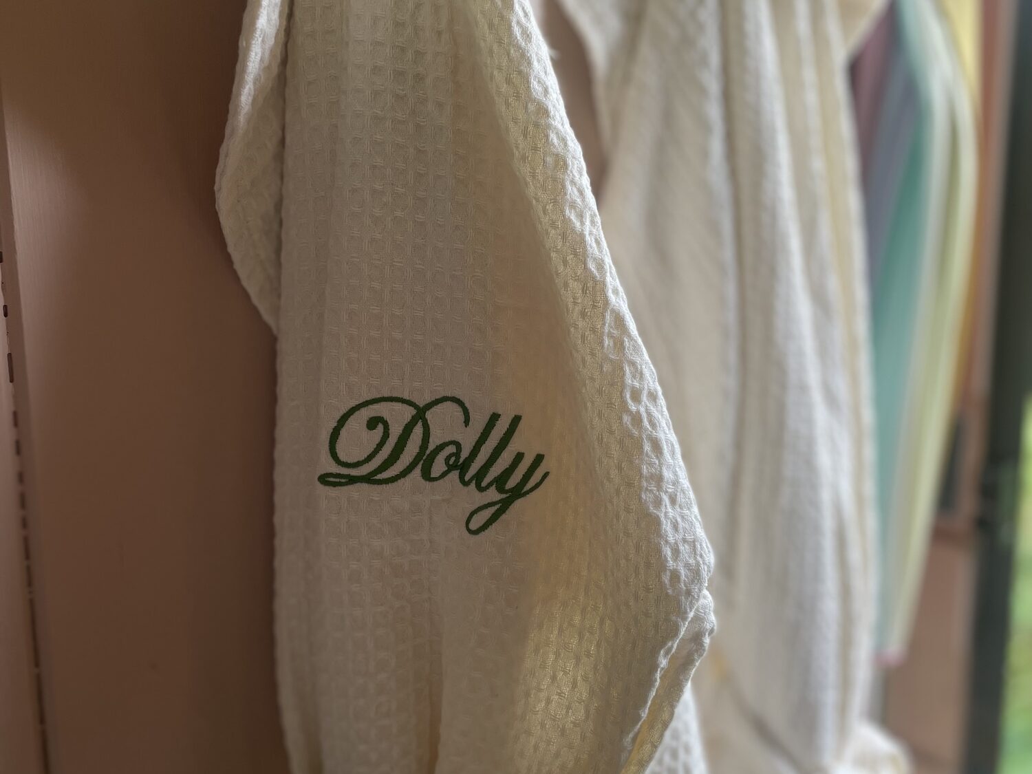 Waffle robes hanging by the door with Dolly embroidered in green thread